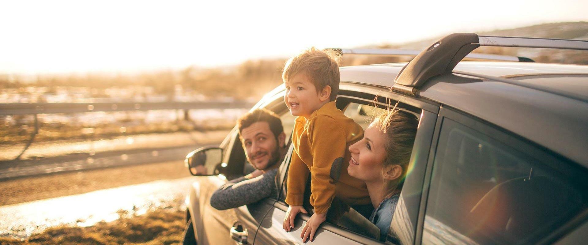 Familie sitter i sin bil og ser på en solnedgang